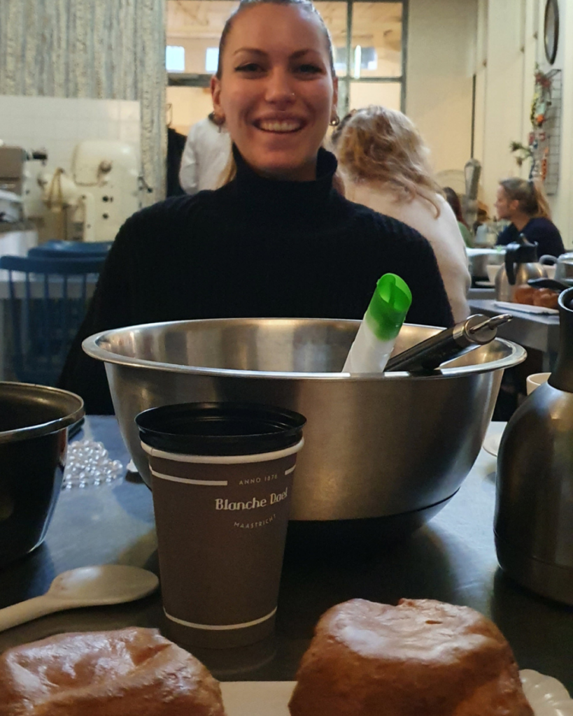 Een vrouw zit aan een tafel bezig met de Bossche Bollen Workshop bij Bakkerij Royal in het historische centrum van Den Bosch