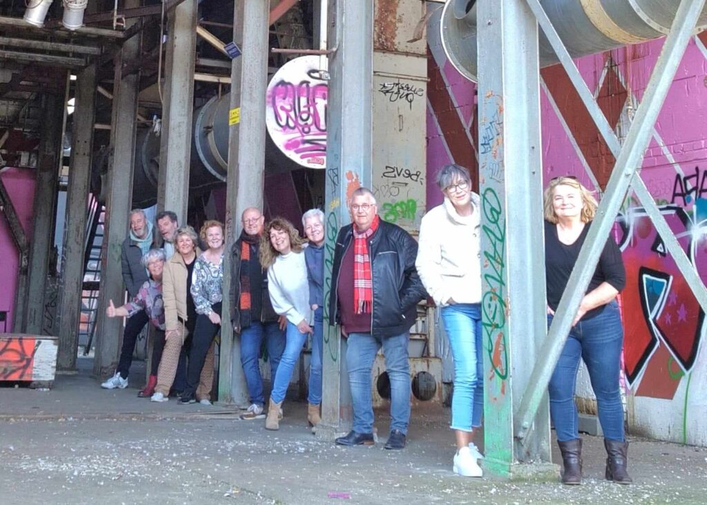 Een groep volwassenen geposeerd voor een groepsfoto tussen de industriele setting op de tramkade in Den Bosch